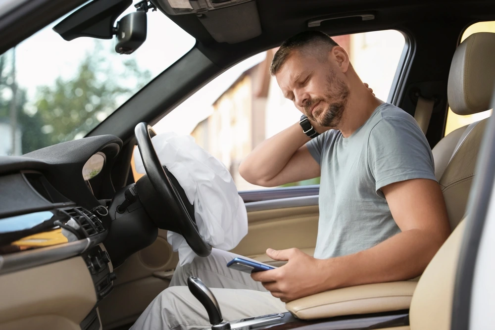 Man suffering from auto accident pain in car, looking for injury chiropractor in Henderson, NV for back pain and neck pain relief.