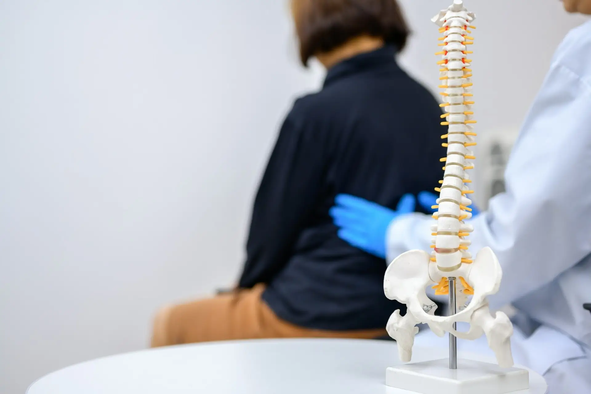 Chiropractor in Henderson treating patient with back pain and neck pain, spine model shows auto accident injury recovery care.