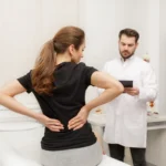 A female patient experiencing lower back pain consulting with a Henderson chiropractor to determine the underlying cause and discuss treatment options.