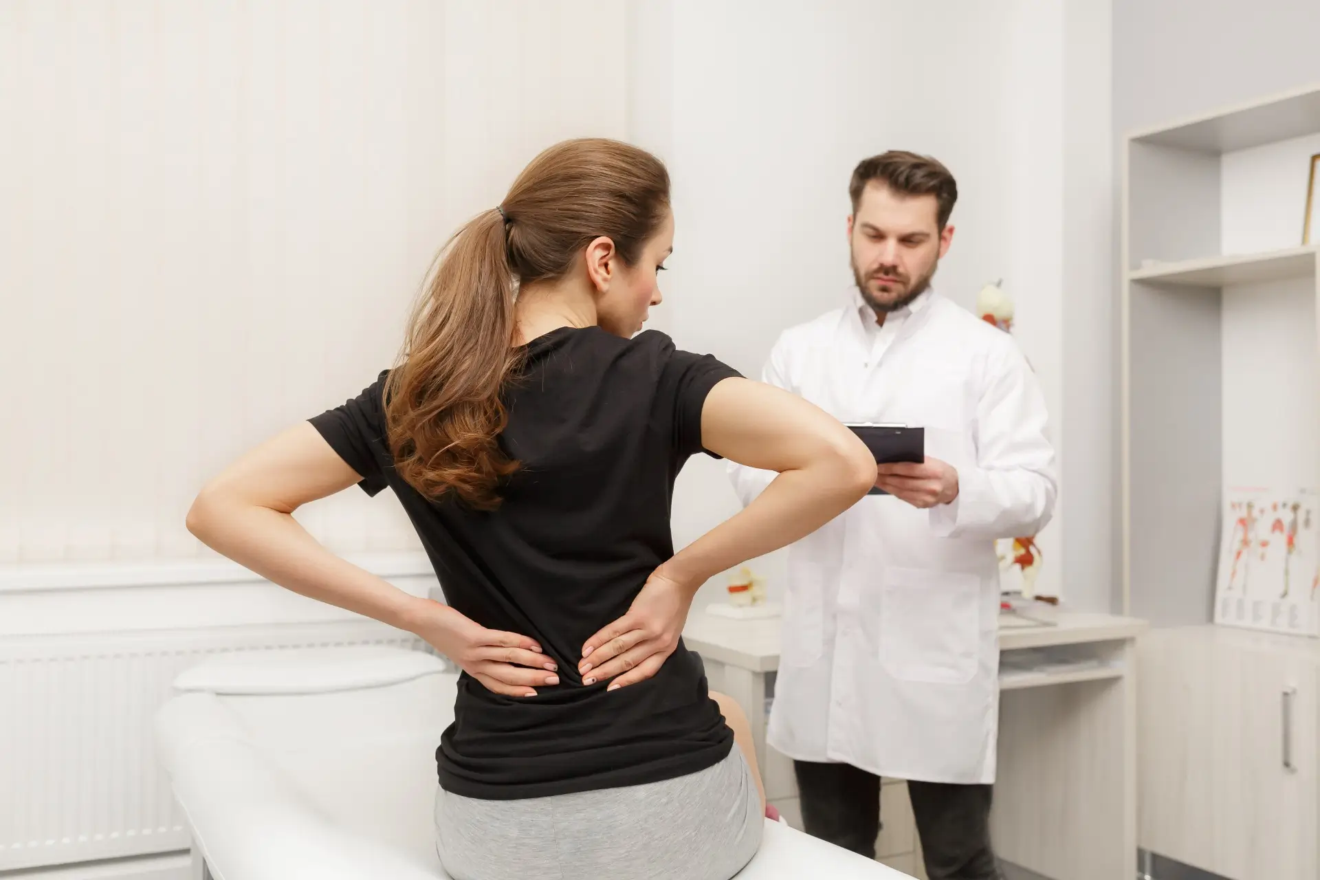 A female patient experiencing lower back pain consulting with a Henderson chiropractor to determine the underlying cause and discuss treatment options.